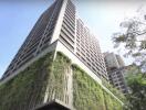 Exterior view of a modern high-rise building with greenery on lower levels