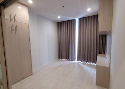 Well-lit bedroom with light-colored curtains and built-in wardrobe