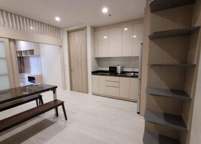 Modern kitchen and dining area with light wood cabinetry and built-in appliances