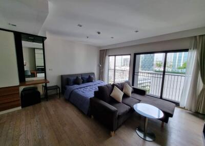 Spacious bedroom with a bed, sofa, and balcony view