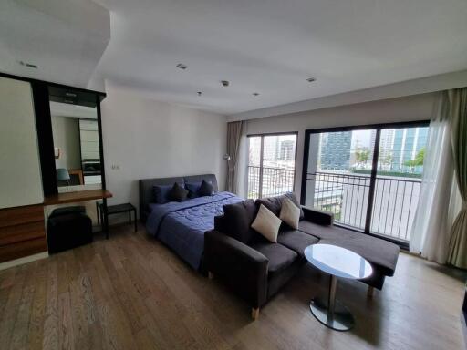 Spacious bedroom with a bed, sofa, and balcony view