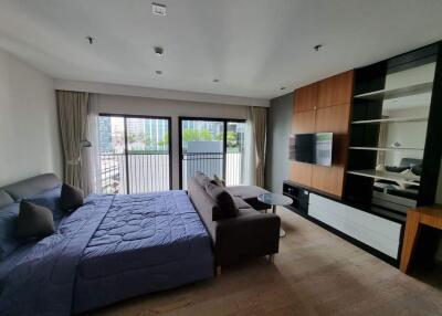 Modern bedroom with large bed, sofa, TV, and balcony view