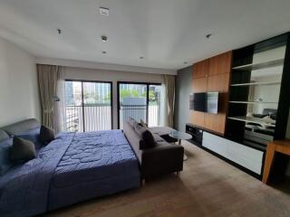 Modern bedroom with large bed, sofa, TV, and balcony view