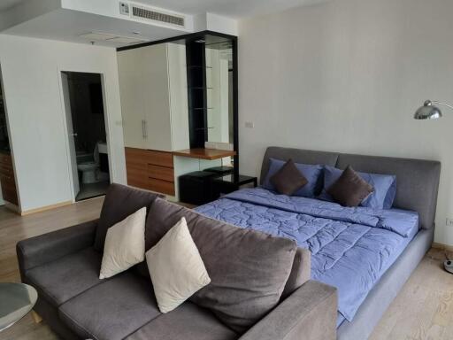 Bedroom with grey couch and blue bedding