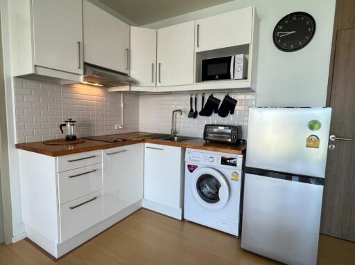 Modern kitchen with white cabinets, appliances, and wooden countertops