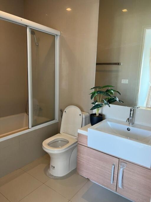 Modern bathroom with a bathtub, toilet, and sink with cabinetry