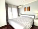 Spacious bedroom with large bed, bedside tables, lamps, and air conditioner