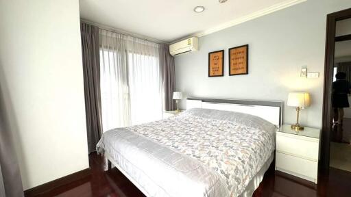 Spacious bedroom with large bed, bedside tables, lamps, and air conditioner