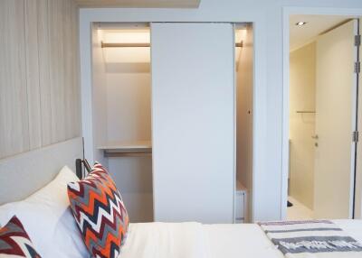 A modern bedroom with an open closet and a partial view of an adjoining bathroom