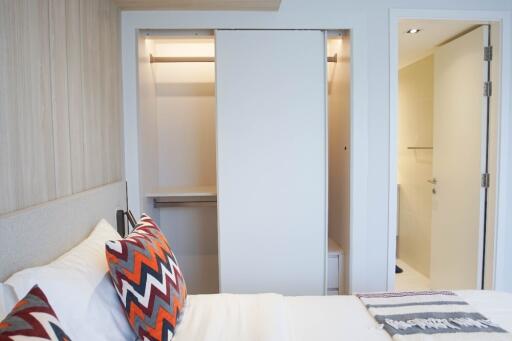 A modern bedroom with an open closet and a partial view of an adjoining bathroom