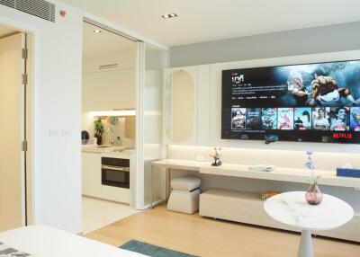 Modern living area with wall-mounted TV and open plan kitchen