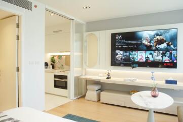 Modern living area with wall-mounted TV and open plan kitchen