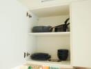 Open kitchen cabinet with dishes and pans