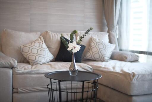 Modern living room with beige sectional sofa, decorative pillows, and a small round coffee table