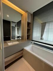 Modern bathroom with a large mirror, sink, bathtub, and window with blinds