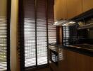 Modern kitchen with brown cabinets and large blinds