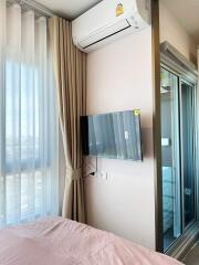 Bedroom with window, curtain, air conditioner, and wall-mounted TV