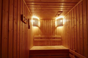 Wood-paneled sauna with built-in wooden benches and warm lighting