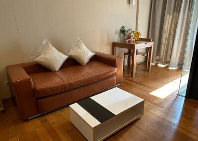 Cozy living room with a brown leather sofa, a coffee table, and a small study area