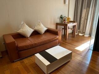 Cozy living room with a brown leather sofa, a coffee table, and a small study area