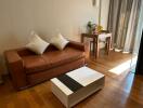 Cozy living room with a brown leather sofa, a coffee table, and a small study area