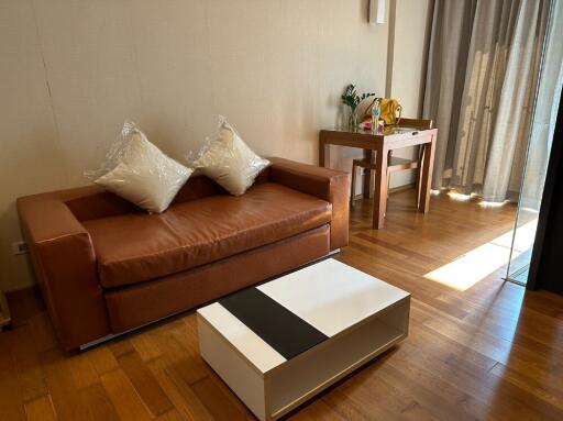 Cozy living room with a brown leather sofa, a coffee table, and a small study area