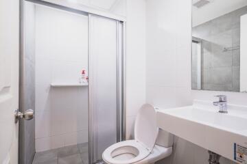 Clean white-tiled bathroom with shower, toilet, and sink