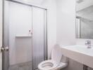 Clean white-tiled bathroom with shower, toilet, and sink