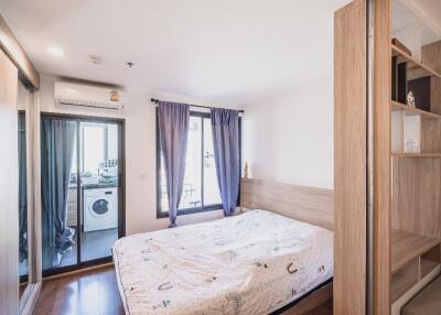 Bedroom with large bed, mirrored closet, and attached laundry room with washing machine