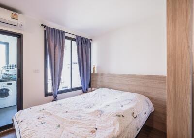 Bedroom with a window and door to a connected balcony with a washing machine