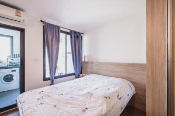 Bedroom with a window and door to a connected balcony with a washing machine