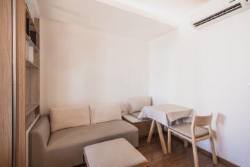 Minimalist living room with a small sofa, table, and chairs.