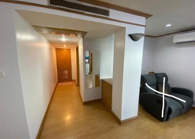 A hallway with wooden flooring, leading to a door.