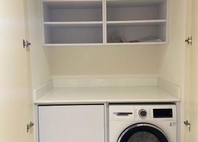 Laundry room with washing machine, storage shelves and a countertop