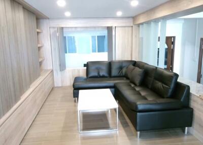 Modern living room with black leather sectional sofa and white coffee table