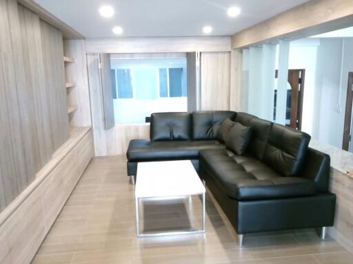 Modern living room with black leather sectional sofa and white coffee table