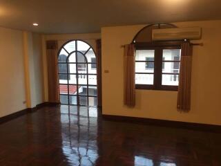 Spacious living room with large arched windows and wooden flooring