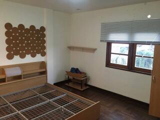 Empty bedroom with wooden bed frame and window