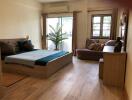 Spacious bedroom with wooden flooring, double bed, and large windows