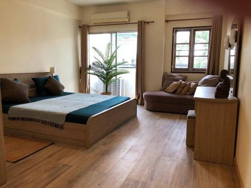 Spacious bedroom with wooden flooring, double bed, and large windows