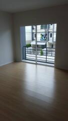 Bright, unfurnished living room with wooden floors and large window