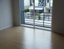 Bright, unfurnished living room with wooden floors and large window