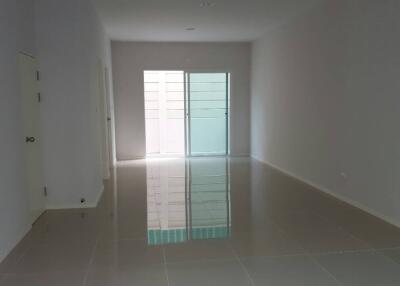 Empty living room with glossy tile flooring and a glass door leading outside