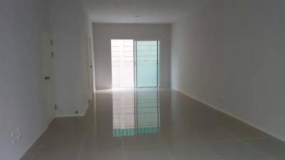 Empty living room with glossy tile flooring and a glass door leading outside