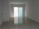 Empty living room with glossy tile flooring and a glass door leading outside