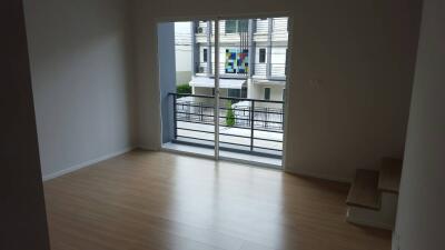 Unfurnished main living area with wooden flooring, sliding glass doors, and access to a balcony