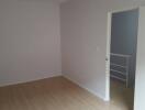 Empty bedroom with light colored laminate flooring and an open door leading to a small landing area