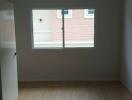 Empty bedroom with window and wooden floor