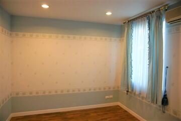 Empty bedroom with hardwood floor and large window with curtains