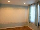 Empty bedroom with hardwood floor and large window with curtains